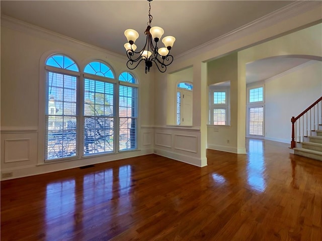 unfurnished dining area featuring a wealth of natural light, stairway, wood finished floors, and ornamental molding