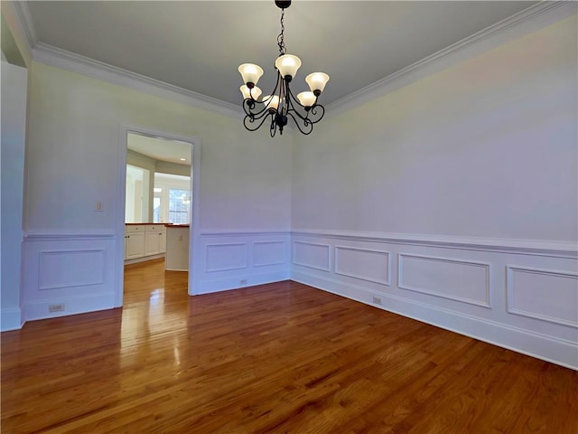 unfurnished room featuring a chandelier, wood finished floors, and ornamental molding