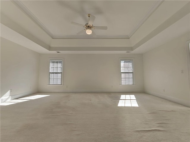 empty room with light carpet, baseboards, a raised ceiling, and crown molding