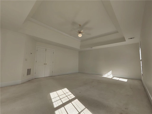 empty room with baseboards, visible vents, and a raised ceiling