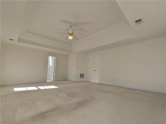 empty room featuring visible vents, a tray ceiling, and light colored carpet