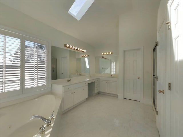 bathroom with a jetted tub, a skylight, high vaulted ceiling, and vanity