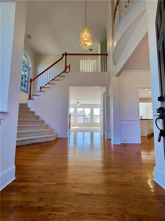 foyer entrance featuring a chandelier, stairway, wood finished floors, and a wealth of natural light