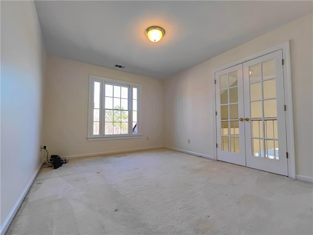 carpeted spare room featuring french doors, visible vents, and baseboards