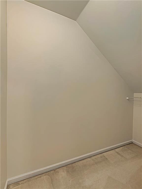 bonus room featuring lofted ceiling, light carpet, and baseboards