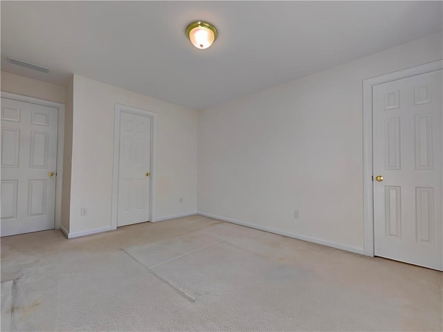 unfurnished bedroom with light carpet, visible vents, and baseboards