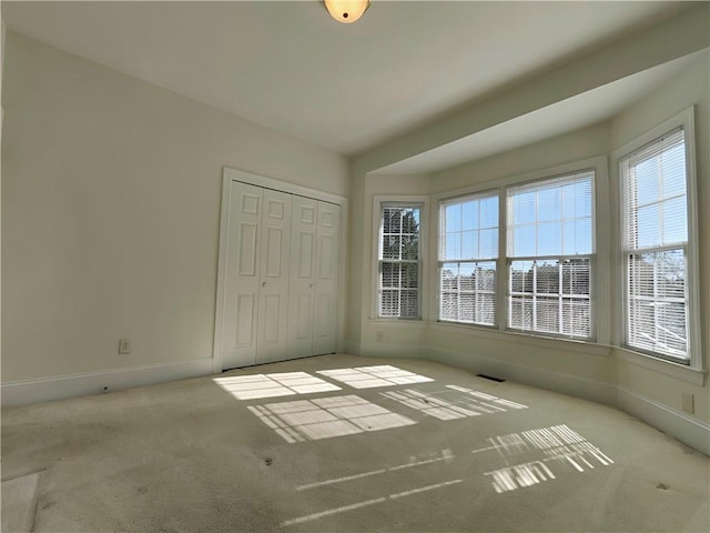 unfurnished bedroom featuring a closet, carpet flooring, visible vents, and baseboards