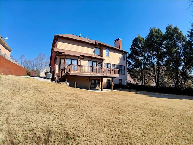 back of house with a deck, a lawn, a chimney, and stairs