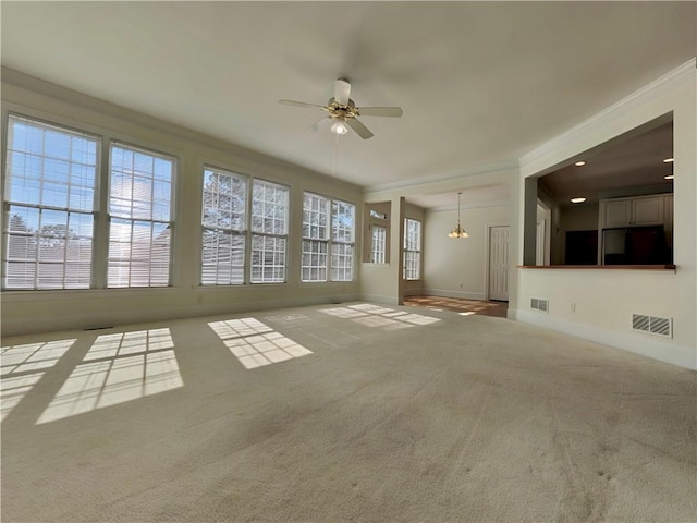 unfurnished living room with visible vents, ornamental molding, carpet flooring, plenty of natural light, and ceiling fan with notable chandelier