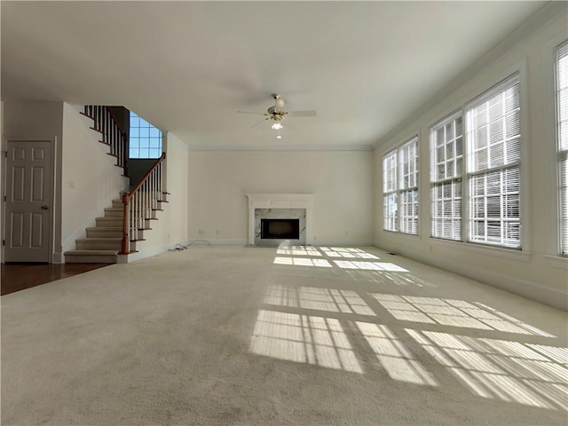 unfurnished living room featuring ceiling fan, a high end fireplace, baseboards, stairs, and carpet