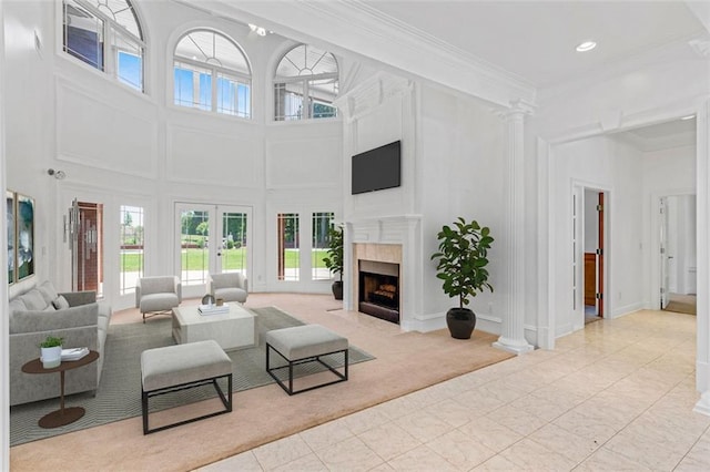 3030 Berry Rd, Loganville, GA 30052 - living area with a towering ceiling, a fireplace with flush hearth, crown molding, french doors, and ornate columns