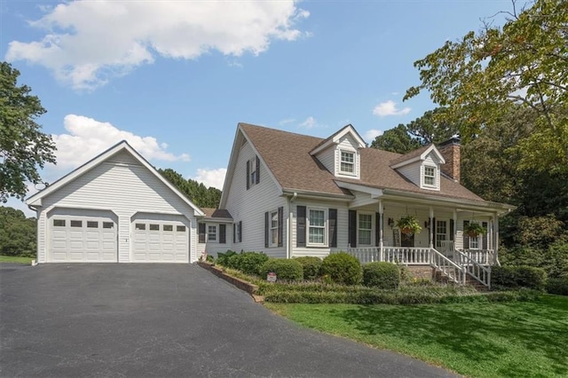 new england style home with a porch, a front yard, and a garage