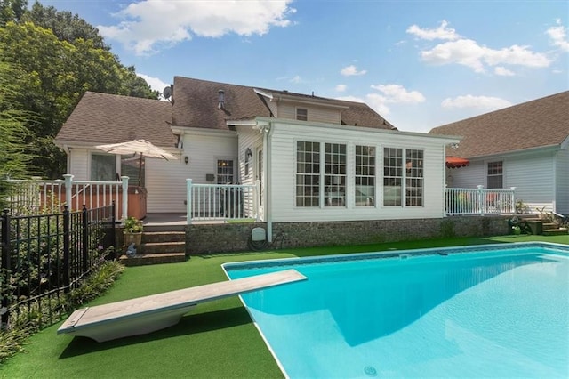 back of property featuring a pool side deck and a lawn