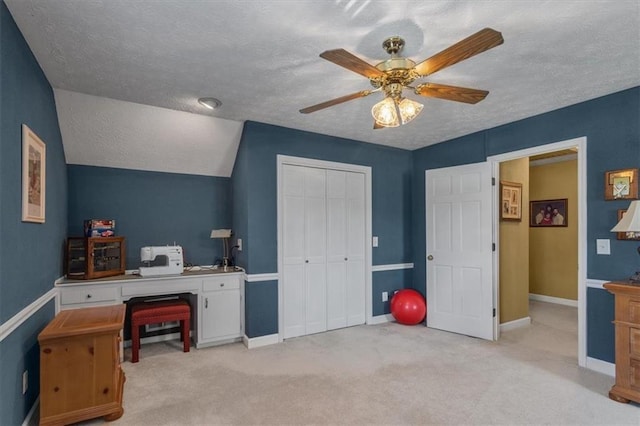 office area featuring ceiling fan, light colored carpet, vaulted ceiling, and a textured ceiling