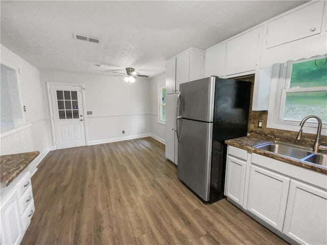 kitchen featuring white cabinetry, wood finished floors, a sink, and freestanding refrigerator