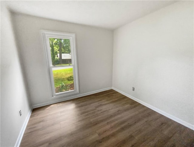 empty room with dark wood finished floors and baseboards