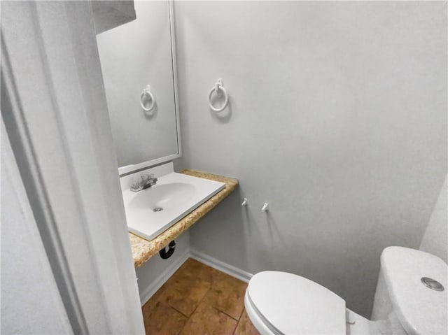 bathroom with toilet, baseboards, a sink, and tile patterned floors