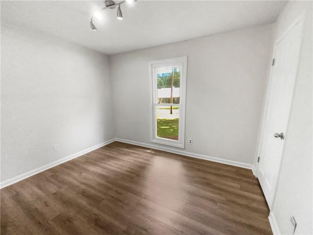 empty room with dark wood finished floors and baseboards