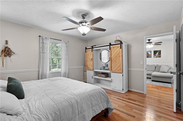 250 Vermont St, Demorest, GA 30535 - bedroom featuring a textured ceiling, wood finished floors, a barn door, a ceiling fan, and baseboards