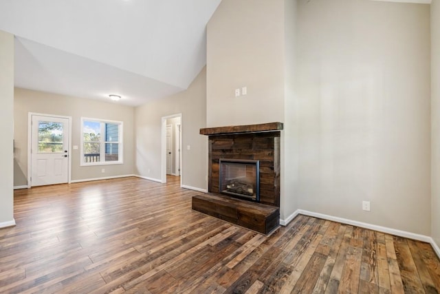 unfurnished living room with high vaulted ceiling, dark hardwood / wood-style flooring, and a fireplace