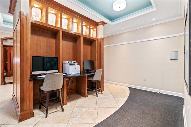 office space with built in desk, ornamental molding, light tile patterned floors, and a raised ceiling