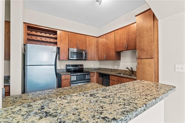 kitchen featuring appliances with stainless steel finishes, kitchen peninsula, stone countertops, and sink