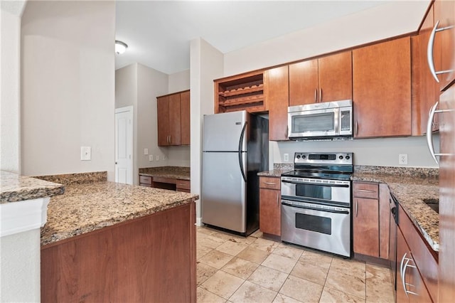 kitchen featuring light stone countertops, appliances with stainless steel finishes, and kitchen peninsula