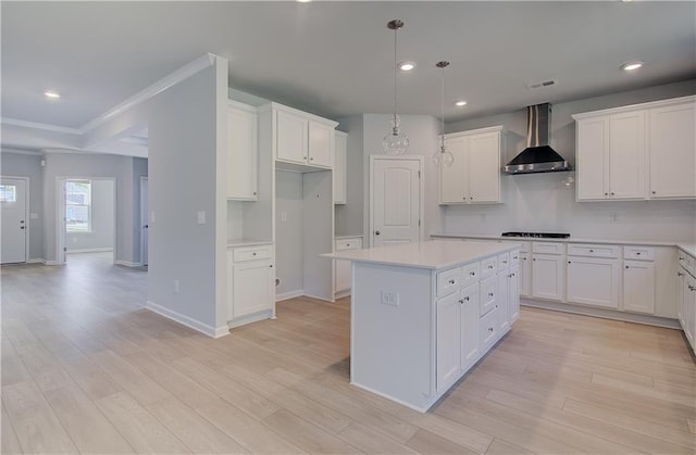 kitchen featuring wall chimney exhaust hood, a center island, black stovetop, white cabinetry, and recessed lighting