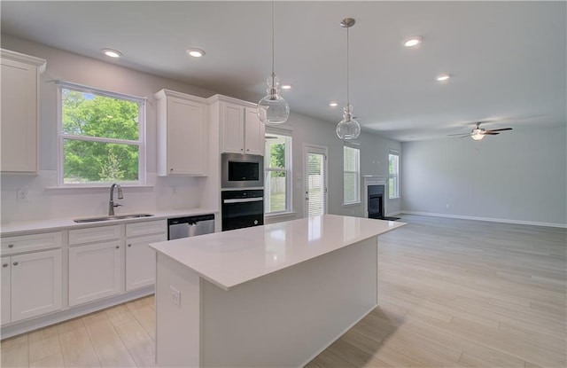 kitchen with a sink, appliances with stainless steel finishes, light countertops, white cabinets, and recessed lighting