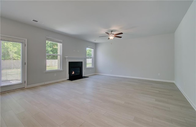 unfurnished living room featuring light wood-style flooring, a fireplace with flush hearth, ceiling fan, and baseboards