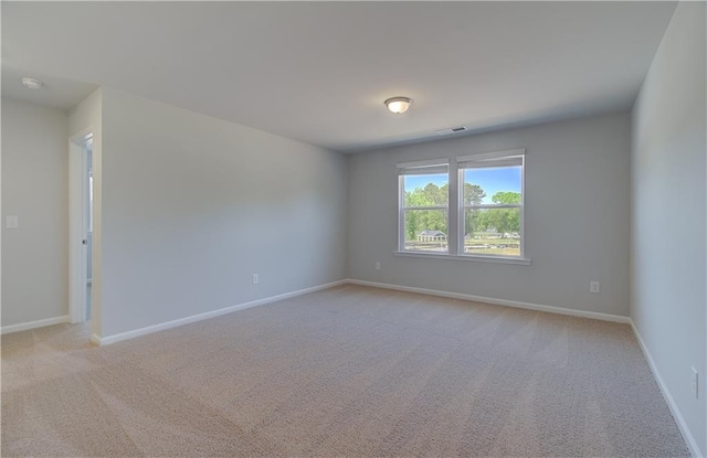 empty room featuring light colored carpet and baseboards