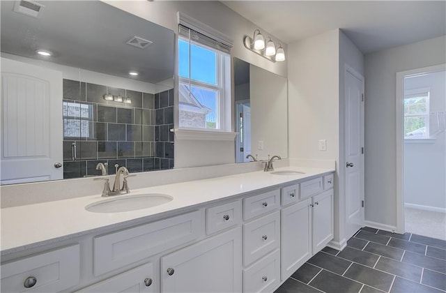 bathroom featuring double vanity, tile patterned floors, and baseboards