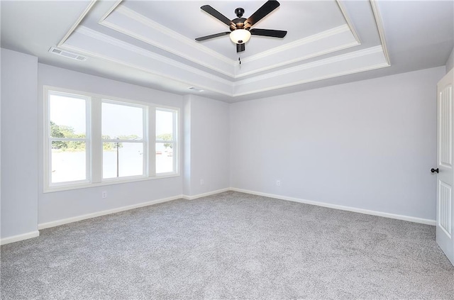 carpeted empty room featuring ornamental molding, ceiling fan, and a raised ceiling