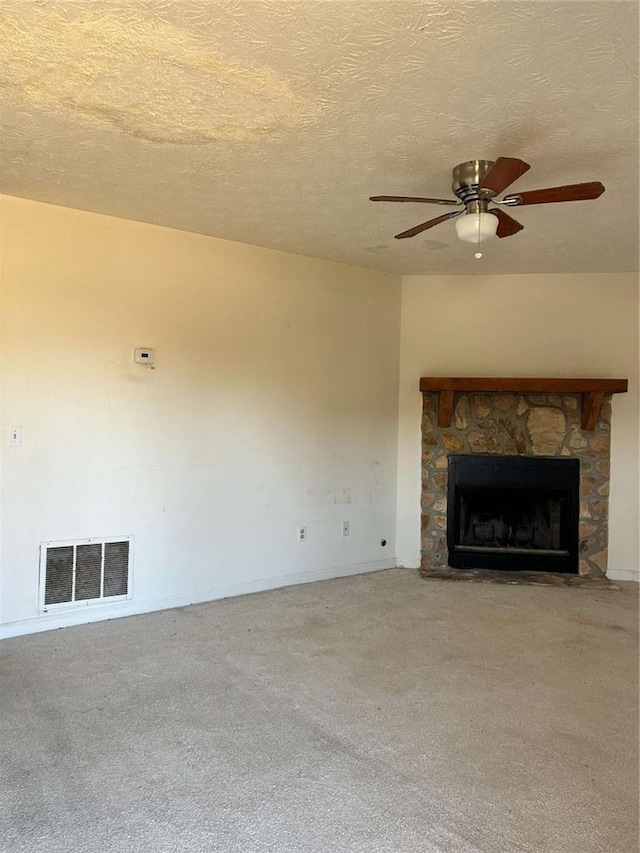 unfurnished living room featuring a textured ceiling, carpet floors, a fireplace, and visible vents