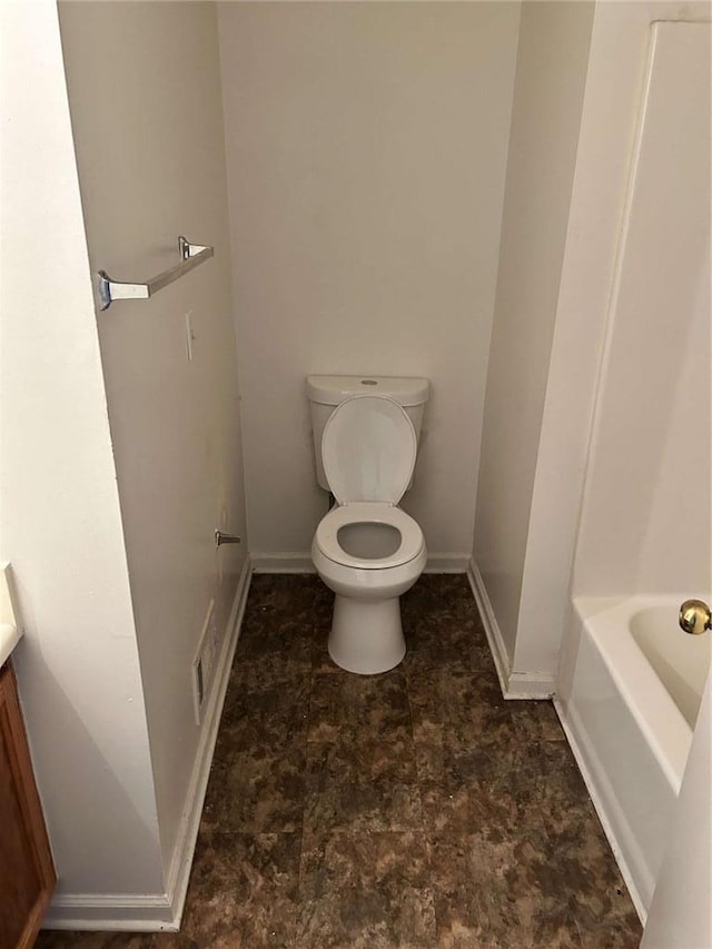 bathroom with baseboards, vanity, toilet, and a bathing tub