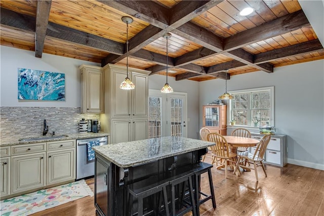 kitchen featuring sink, light stone counters, stainless steel dishwasher, a kitchen island, and cream cabinets