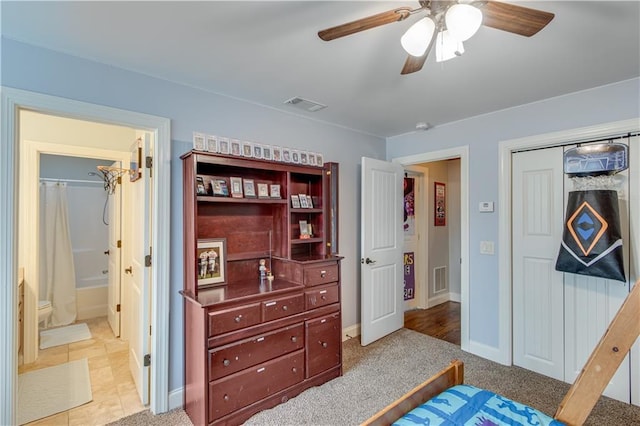 carpeted bedroom with ceiling fan, a closet, and ensuite bath