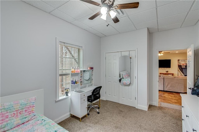 bedroom featuring light carpet, a paneled ceiling, a closet, and ceiling fan