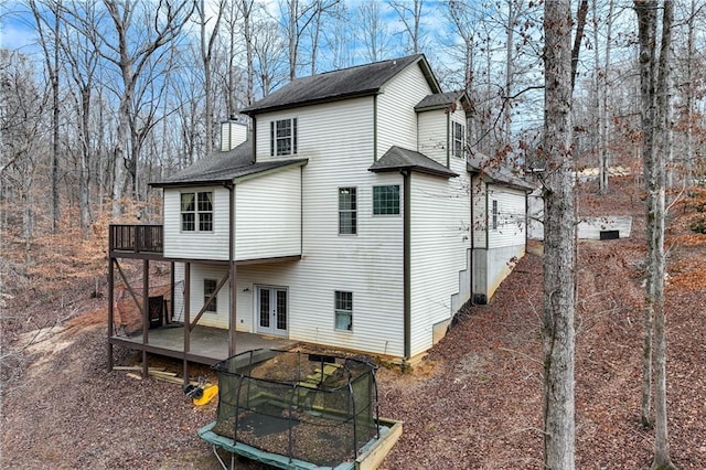 back of house with a trampoline, a wooden deck, and french doors