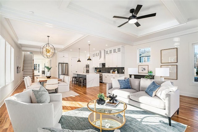 living room with sink, light hardwood / wood-style floors, ceiling fan with notable chandelier, and ornamental molding