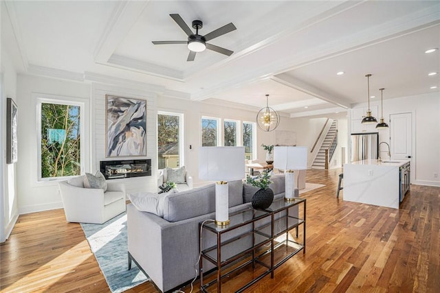 living room with ceiling fan with notable chandelier, sink, plenty of natural light, and light hardwood / wood-style floors