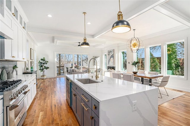 kitchen featuring ceiling fan with notable chandelier, pendant lighting, white cabinets, appliances with stainless steel finishes, and sink