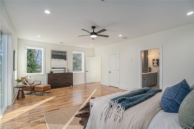 bedroom with ceiling fan, multiple windows, connected bathroom, and light hardwood / wood-style flooring