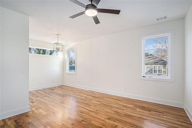 spare room with hardwood / wood-style flooring and ceiling fan with notable chandelier