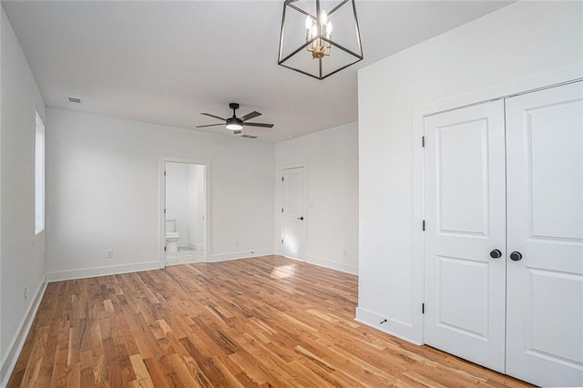 unfurnished room with light wood-type flooring and ceiling fan with notable chandelier