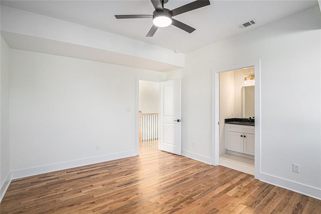 unfurnished bedroom with ceiling fan, sink, hardwood / wood-style flooring, and ensuite bath