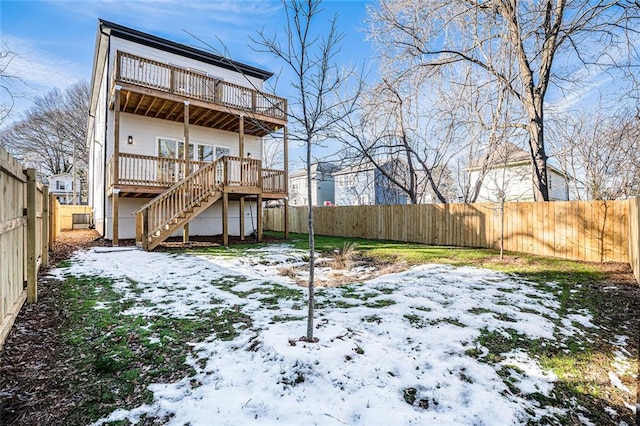 snow covered back of property with a wooden deck