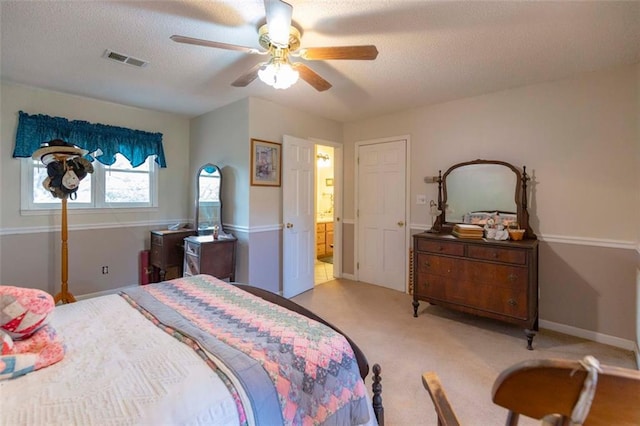 bedroom featuring ceiling fan, connected bathroom, light carpet, and a textured ceiling