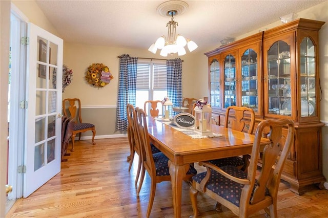 dining area with light hardwood / wood-style floors and a chandelier