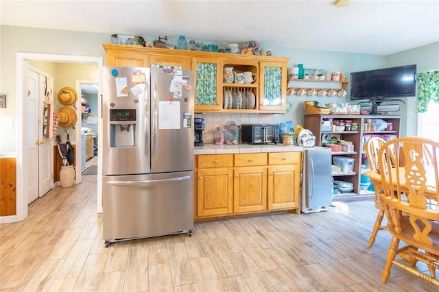 kitchen with tile counters, light hardwood / wood-style floors, and stainless steel fridge